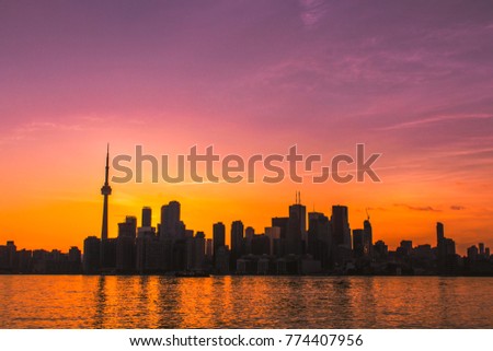 TORONTO CITY SKYLINE AT SUNSET - Downtown Toronto cityscape at sunset under colorful summer skies, waterfront and harbor in foreground. Purple, pink and orange sky. Toronto, Ontario, Canada