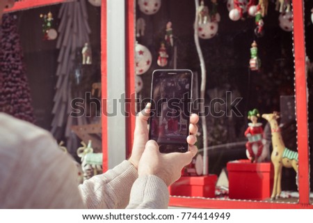 Close up on buyer hands using mobile phone choosing selecting purchase, taking picture of display window. Back side view photography of adult man tourist street shopping