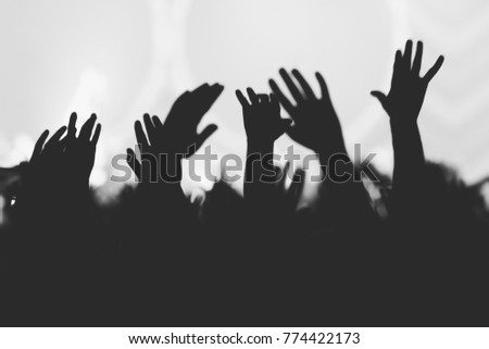 Hands silhouettes of the crowd raised up at music show. Black and white picture