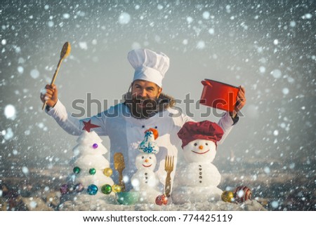 new year christmas snow concept Cook shouting, snowmen and snow xmas tree on blue sky. Cooking and diet concept. Christmas and new year holidays food. Man holding spoon and red pot. Hipster chef hat