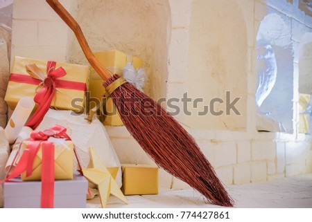 the presents with magic witch’s broom on the floor with copy space in chrismas day. the gifts box and star on the floor.