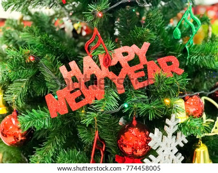 Happy New Year Sign Hanging on Christmas Tree with Red Balls, Music Notes and Snowflake