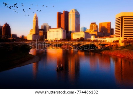 Birds fly over the Scioto River while fishermen glide by on a boat below