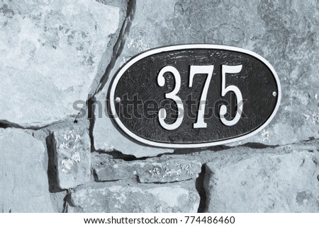 the number 375 in black and white on a stone wall