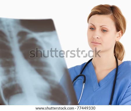 Concentrated female doctor looking at an X-ray on a white background