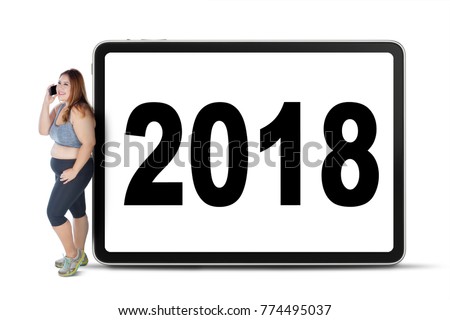 Picture of obesity woman speaking on the mobile phone while leaning with number 2018 on the board
