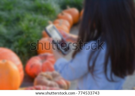 blurry picture of little girl holding smart phone with pumpkins background, filtered tones 