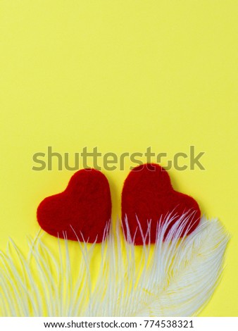Two red wool hearts feather white yellow background Valentines day