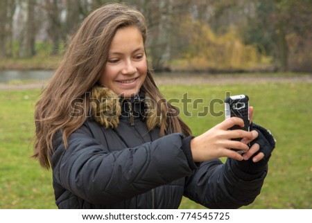 girl takes pictures with her mobile phone in park