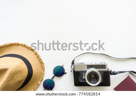 Top view of wooden table with accessories, passport, film camera, wicker hat and sunglasses on wooden table - travel concept.