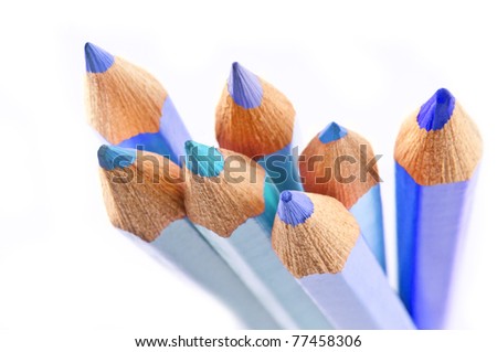 Close up of the ends of a group of pale blue coloured artist pencils arranged over white