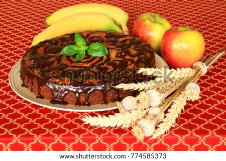 chocolate cake with apples and bananas sitting on a table with a red tablecloth stock photo