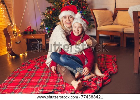 Child with mom near christmas tree at home. Merry christmas and happy New year!