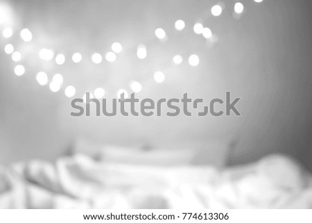 Christmas lights festive decorations. Christmas garlands hanging over bed. White apartment interior design. Christmas interior background. Perfect for greeting cards, decor and holiday mood.