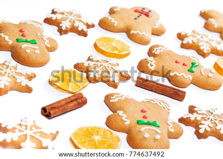 Christmas gingerbread men and snowflakes with lemon and cinnamon sticks on white background. A symbol of winter and new year holidays.