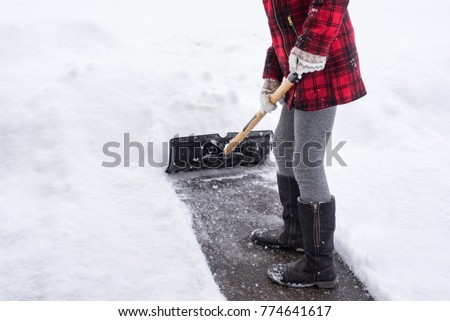Close up of a young woman shoveling a snow covered drive way in Canada.