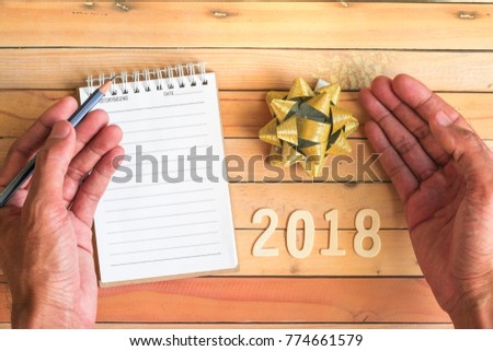 notepad with pencil, gift ribbon and number 2018 on wood backgorund for happy new year image. And welcome new year photo.