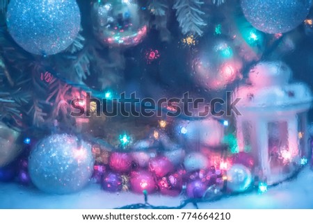 Abstract photo with the effect behind the wet glass of the Christmas tree with garlands and lights and a flashlight. blurred image without focus. New Year's Christmas holiday screensaver, background.
