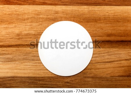A photo of a round white business card on a rustic wooden texture. A mockup or a minimalist banner with copy space