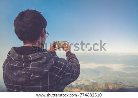 Traveler man take a photo by smart phone on the top of mountain in thailand