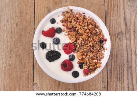 Composition of a typical genuine breakfast made with yogurt, blueberries, raspberries, blackberries, muesli. Concept of: fitness, diet, wellness and breakfasts.