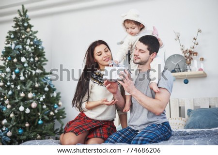 Happy family at christmas in morning opening gifts together near the fir tree. The concept of family happiness and well-being.