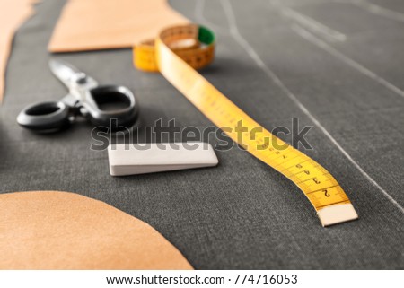 Measuring tape and tailor chalk on grey fabric, closeup