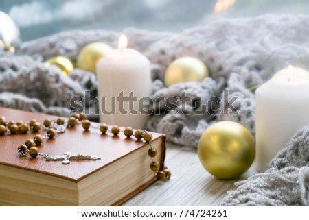 White holiday candles glowing behind Bible wooden cross rustic wood background; Christmas, Easter and religious background with copy space