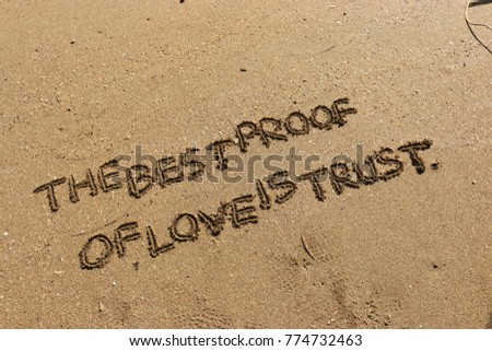 Handwriting  words "THE BEST PROOF OF LOVE IS TRUST." on sand of beach.