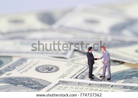 Miniature people: businessman shaking hand with partner (Financial and Business competition concept)
