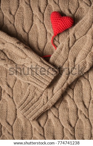 red crochet heart on a background of knitting sweaters. heart in hands. Valentine's Day. Symbol of love.