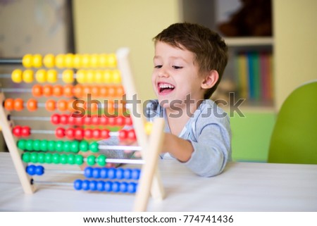 Happy kid playing with abacus toy at kindergarten. Adorable smart child learning to count. Early kids development. Royalty-Free Stock Photo #774741436