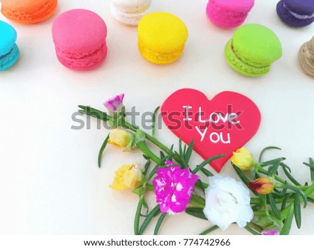 Delicious colorful macarons with decoration pastel flowers and red heart are beautiful on yellow background