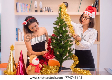 Work with the Christmas atmosphere. Office girl decorated Christmas tree in the office. They are very fun. Christmas and New Year in the office.
