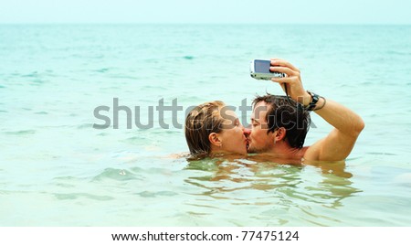 Man kissing the girl and taking the picture of them self in the sea