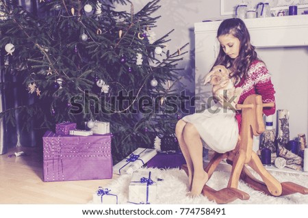 Little girl playing at Christmas tree with rabbit