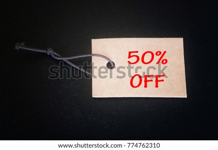 Paper tag written 50% off over black background