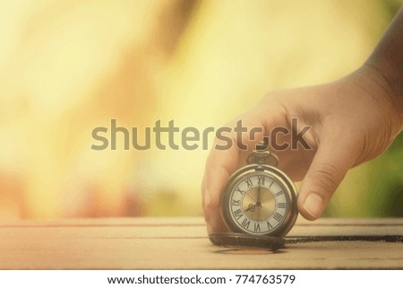 close up hand holding pocket watch on old wood table with nature copy space background for text, manage time for success business and holiday concept, process vintage tone