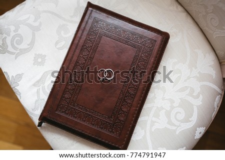 Silver wedding rings lie on the book in leather cover