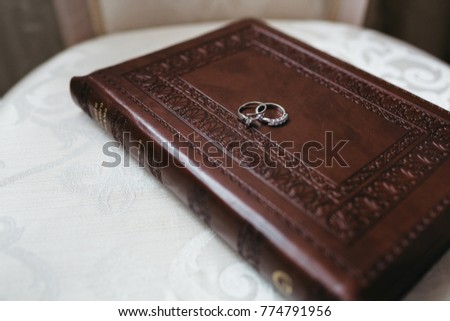 Silver wedding rings lie on the book in leather cover