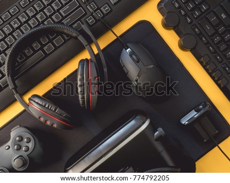 gamer workspace concept, top view a gaming gear, mouse, mouse mat, keyboard, joystick, headset, on yellow table background with copy space