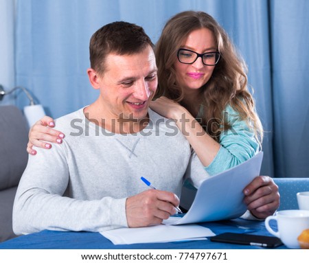 Middle-aged couple signing beneficial financial agreement together at home