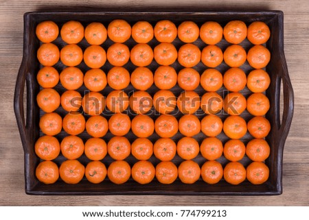Fresh orange, tangerine fruit, mandarin pattern background on a wooden tray, close up, top view