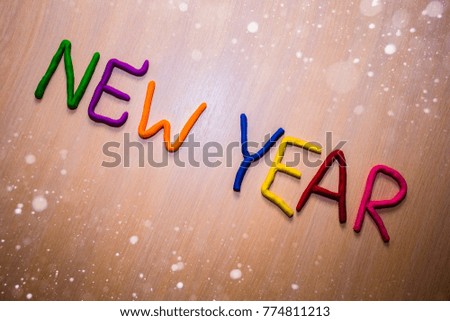 New Year message from colorful bright plasticine on a light wooden background with snow. Colorful bright New Year background 