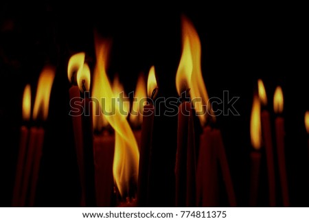 Candles burning on dark background, close up