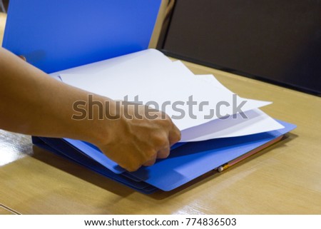 Business Man putting white paper in blue file document in work office - business concept 