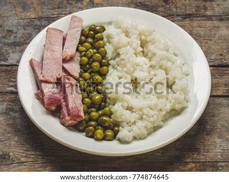 A bowl of boiled rice, peas and meat - a serving (set).
