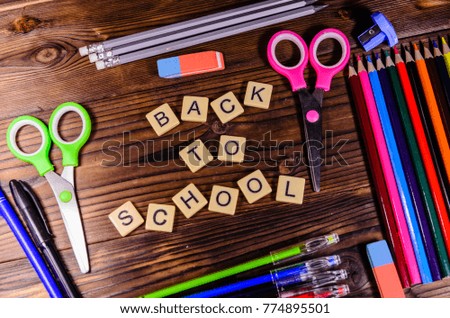 Set of different school stationeries. Pens,  scissors, pensils, eraser on wooden desk. Back to school inscription. Top view