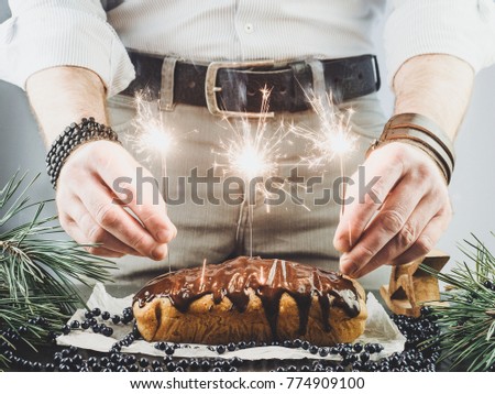 Young guy fomenting Bengal lights on a background of a Christmas biscuit cake