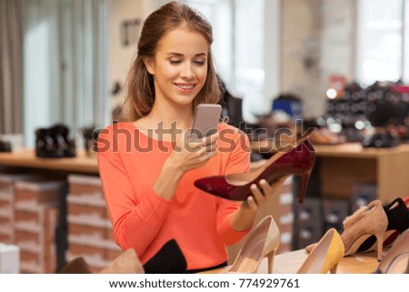sale, shopping, fashion and people concept - happy young woman taking photo by smartphone at shoe store